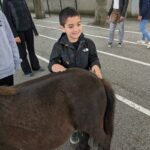 Un enfant de l'UEMa caresse un poney brun en souriant
