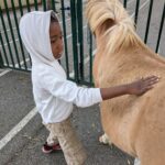 Un enfant de l'UEMa caresse un poney beige