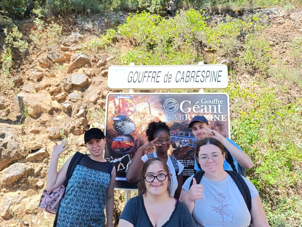 Cinq personnes devant le panneau du gouffre géant de Cabrespine