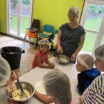 Des enfants, charlotte sur la tête, autour d'une table, en atelier cuisine