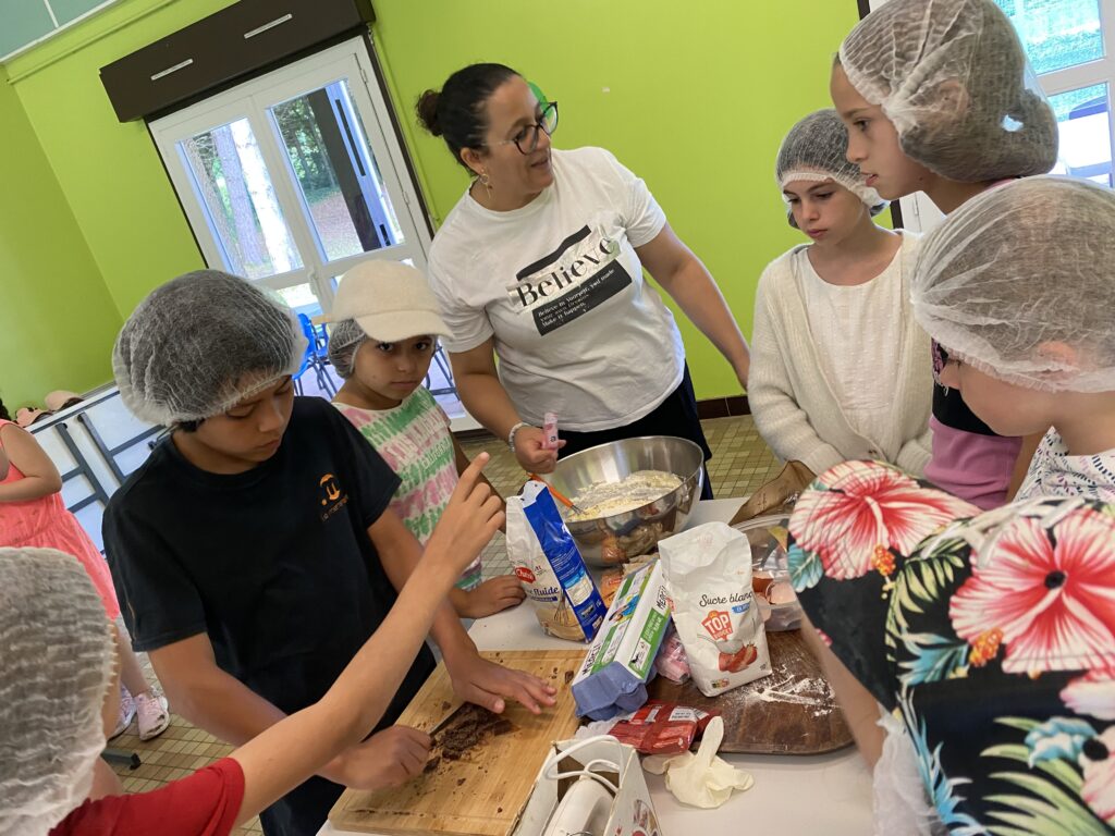 Des enfants et une animatrice, autour d'une table, en atelier cuisine