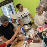 Des enfants et une animatrice, autour d'une table, en atelier cuisine