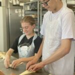 Une jeune fille et un jeune homme confectionnent des chocolatines