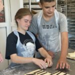 Une jeune fille et un jeune homme confectionnent des chocolatines