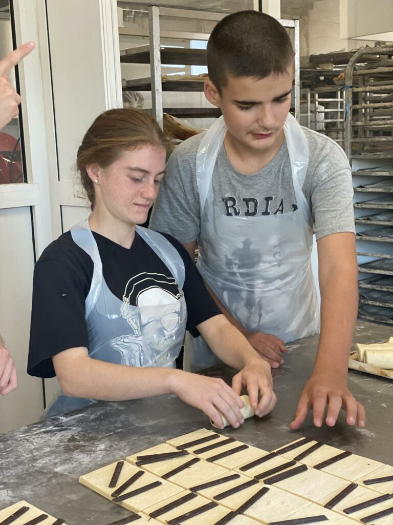 Une jeune fille et un jeune homme confectionnent des chocolatines