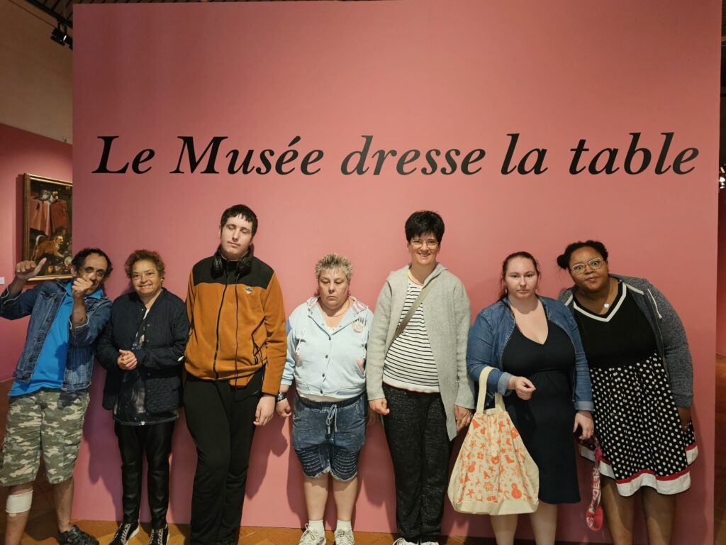 Le groupe pose devant le mur "Le Musée dresse la table"