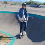 Une jeune fille sur le parcours de pumptrack avec sa trottinette