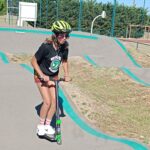 Une jeune fille sur le parcours de pumptrack avec sa trottinette