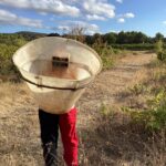 Une personne de dos porte une hotte à vendanges