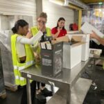 3 jeunes filles mettent des bouteilles dans des cartons