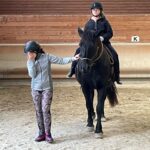 Une jeune sur un cheval, une autre jeune tient la longe