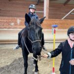 Un jeune sur un cheval, une autre jeune tient la longe