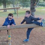 Deux jeunes sur une poutre en bois du parcours de santé