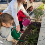 Deux élèves, avec 2 membres de l'encadrement, arrosent la jardinière