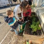 Deux élèves, auprès de leur enseignante, finalisent la jardinière