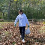 Une jeune, avec des gants et un sac bien rempli de châtaignes