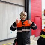 Un jeune, en tenue de pompiers, avec le casque visière, lève les deux pouces en l'air