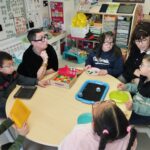 5 jeunes avec 2 de leurs encadrantes autour d'une table d'activités