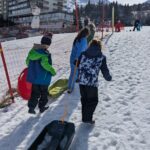 Les enfants tirent leurs luges vers le haut de la piste pour pouvoir redescendre en luge