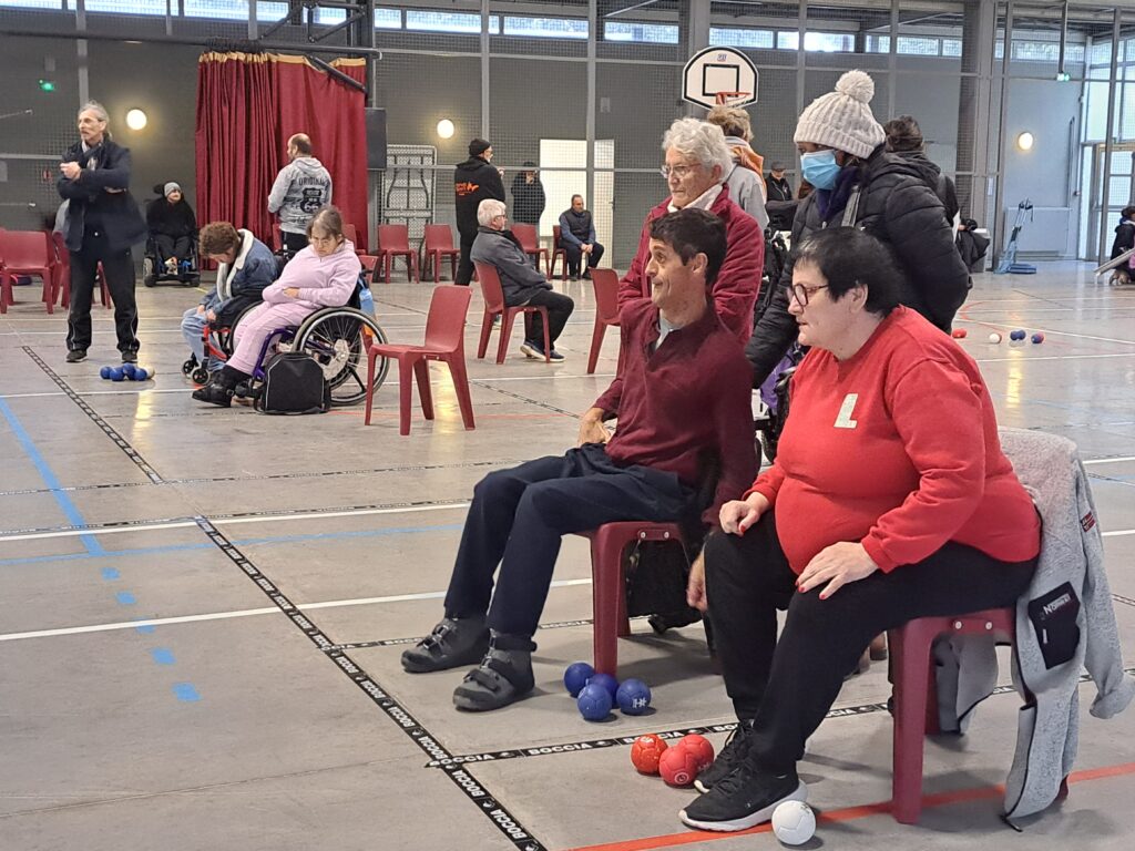 Dans le gymnase, des joueurs durant la compétition de boccia, encouragés par des spectateurs