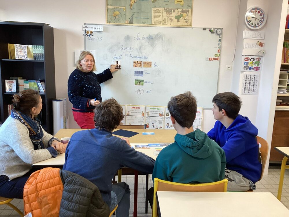 En salle de classe, Delphine, au tableau explique aux élèves les énergies