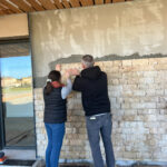 Deux personnes posent des pierres sur le mur