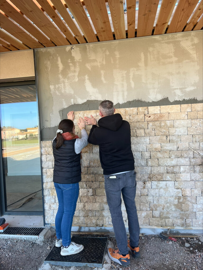 Deux personnes posent des pierres sur le mur