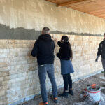 Deux personnes posent des pierres sur le mur