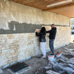 Deux personnes posent des pierres sur le mur