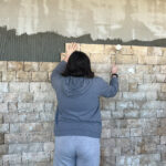 Une jeune fille pose une pierre sur le mur